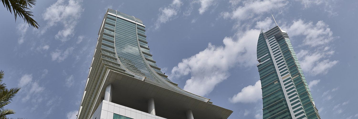 The iconic Bahrain Financial Harbour, a striking example of modern architecture with its twin towers soaring into a blue, cloud-dotted sky—home to prestigious Servcorp serviced offices,