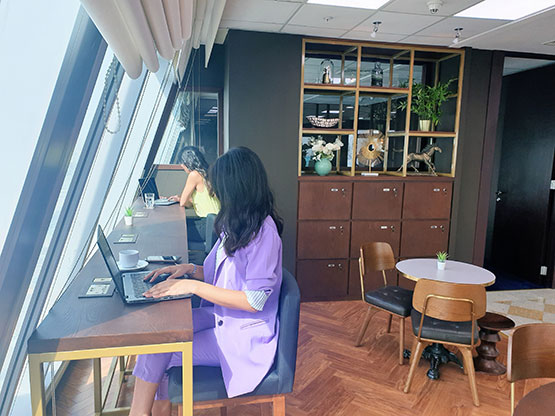 A professional working at Bahrain Financial Harbour with a laptop in a sunlit Servcorp coworking space