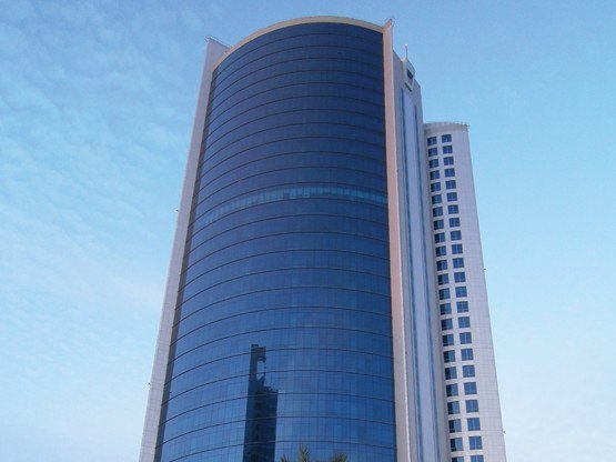 The iconic Bahrain Financial Harbour, a striking example of modern architecture with its twin towers soaring into a blue, cloud-dotted sky—home to prestigious Servcorp serviced offices,