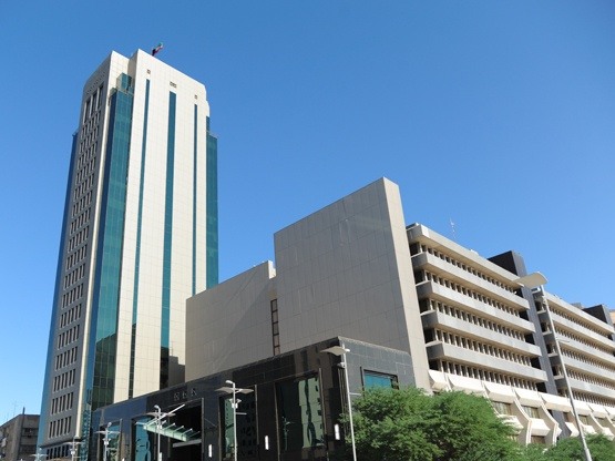 Sahab Tower in Kuwait, a tall, modern office building with a sleek glass façade, standing prominently against a clear blue sky alongside surrounding government and commercial buildings.