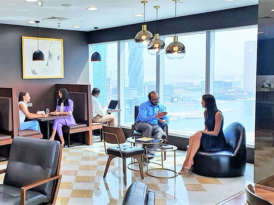A stylish and welcoming Servcorp business lounge with panoramic city and waterfront views, where professionals are seen networking and relaxing
